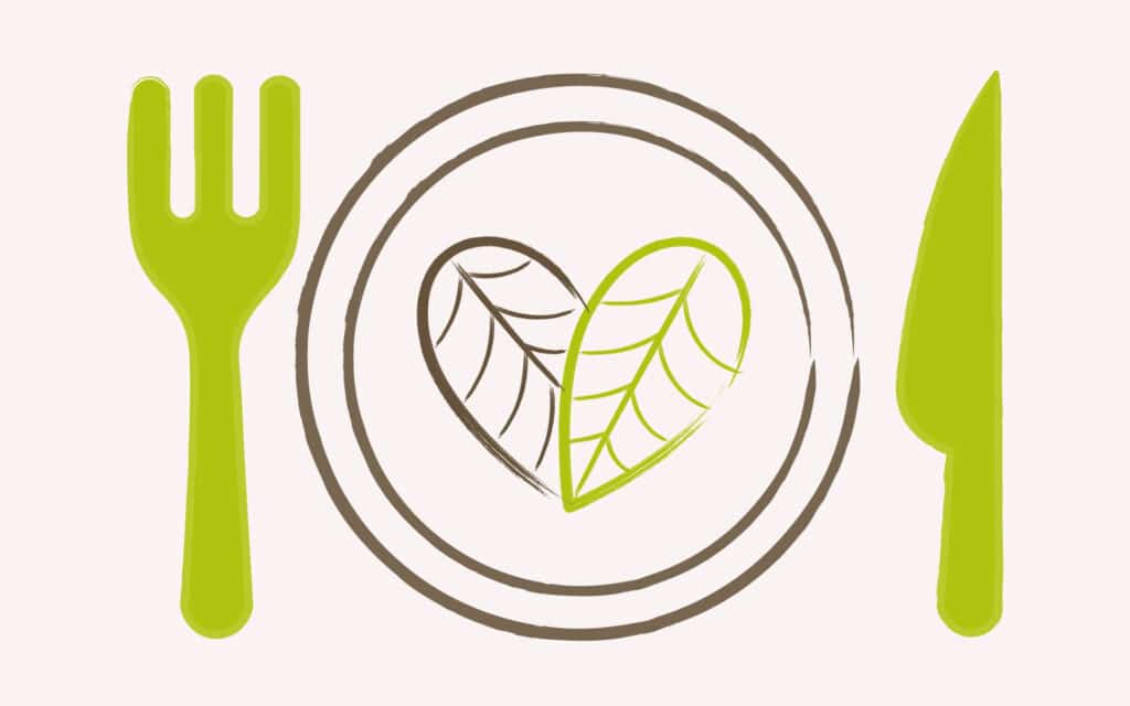 Ein Teller, rechts und links daneben liegen Messer und Gabel. Auf dem Teller befindet sich ein aus Blättern geformtes Herz, um den Stellenwert bewusster Ernährung zum CO₂ Ausgleich hervorzuheben.