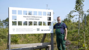 Begrüßungsschild im IONIQ Wald mit Mitarbeiter