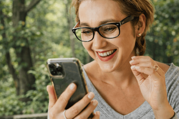 Lächelnde Frau schaut zufrieden auf ihr Handy